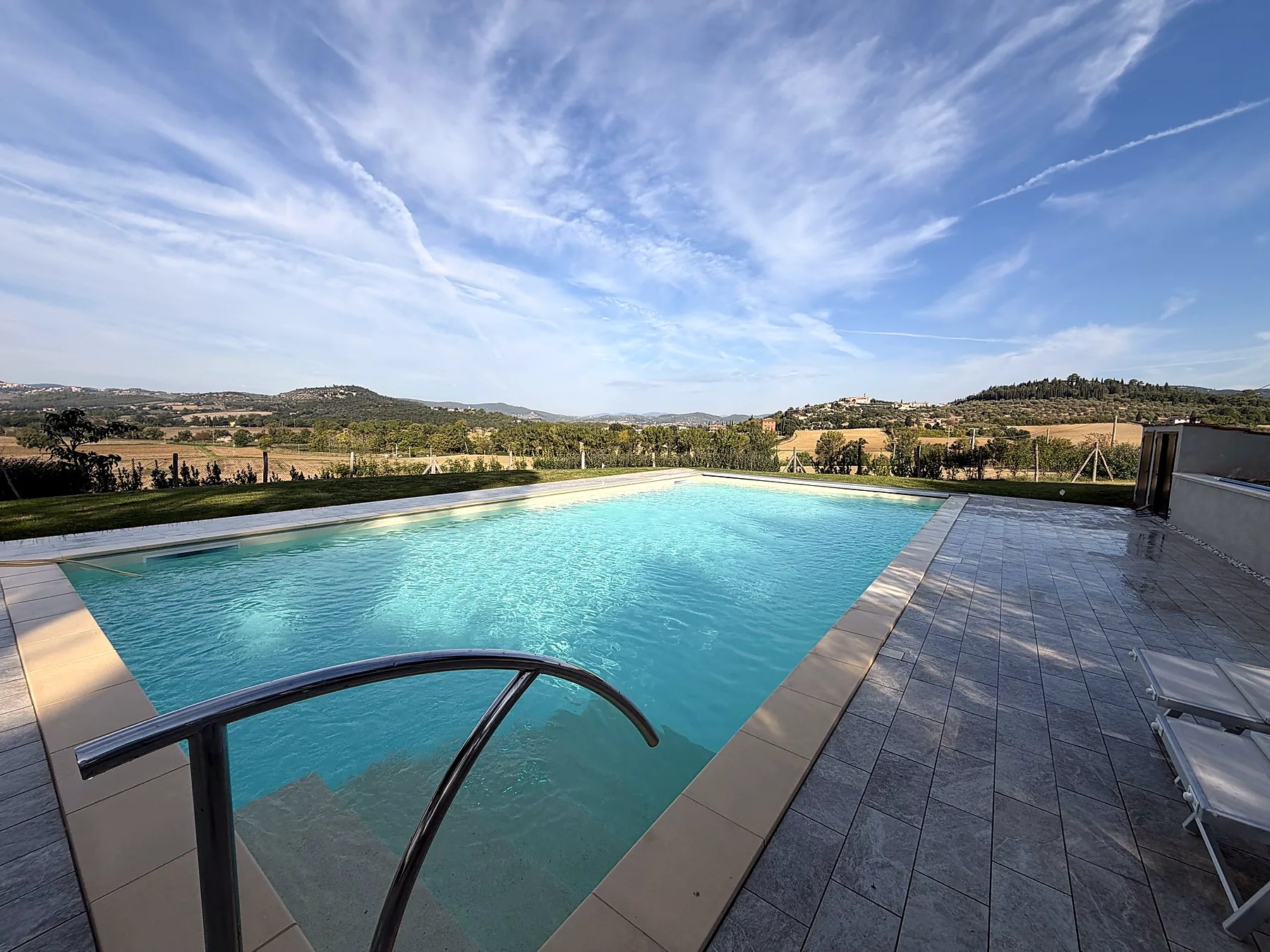 Rechteckiger Pool mit Rasen, Steinterrasse und Blick auf die umbrischen Hügel